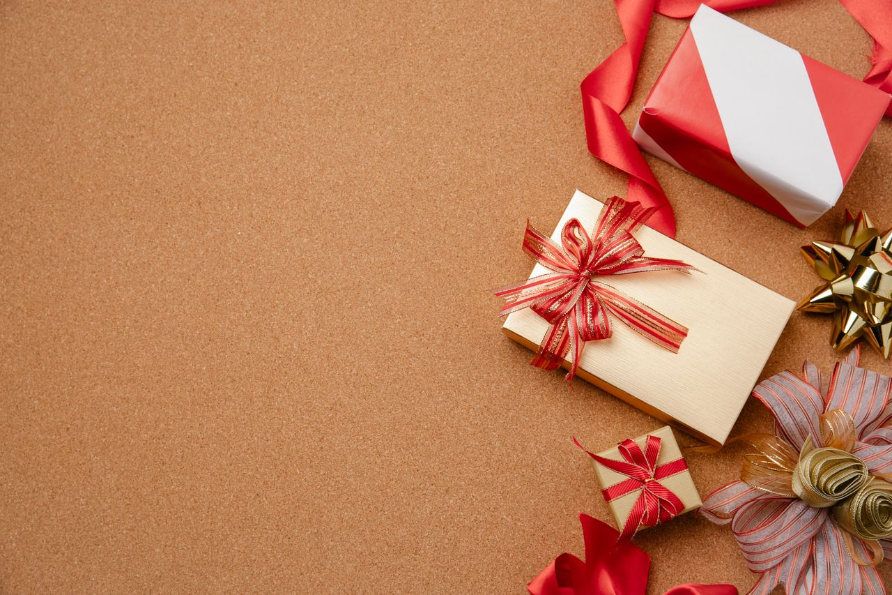 Top view of festive gift boxes with ribbons on brown background, perfect for holiday themes.